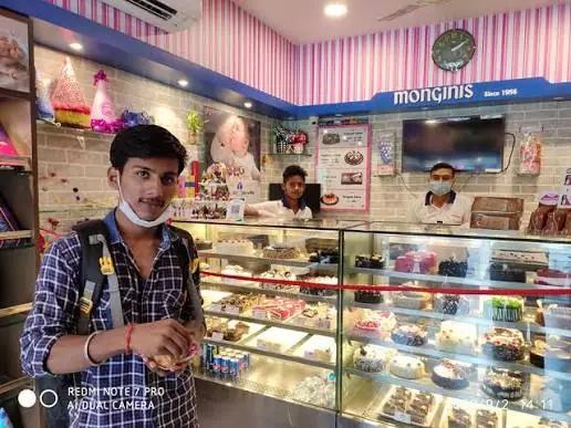 Customer beside a lit cake display with staff behind the counter
