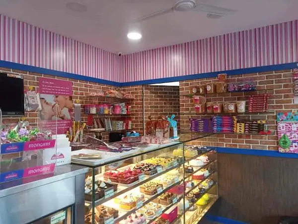 Pink-striped Monginis shop with a refrigerated display counter