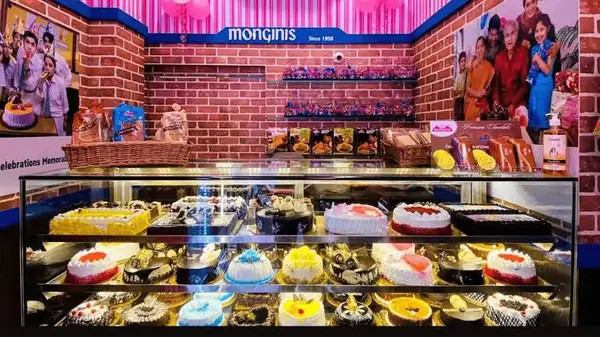 Decorated cakes displayed beneath a Monginis sign